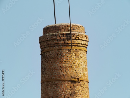 top of a red brick chimney with steel lightning rods on a sunny April day