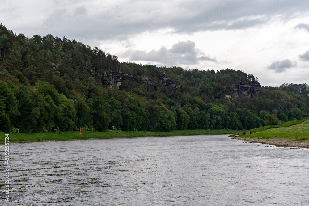A river with a cloudy sky in the background. The water is calm and the trees are lush A river with a cloudy sky in the background. The water is calm and the trees are lush