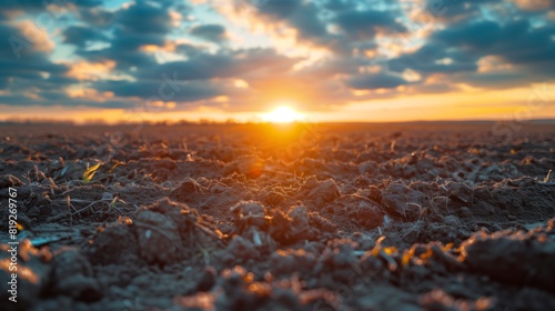 Breathtaking sunrise over a barren, plowed field, with dramatic clouds and vibrant colors in an agricultural landscape.