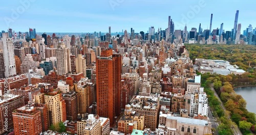 High-rise orange building standing out in the scenery with similar architecture. Skyline with beautiful skyscrapers is at backdrop. Aerial view on New York, USA at day.