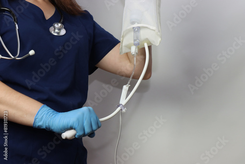 Professional wearing gloves holding the pressure bag connected with Iv bag line 