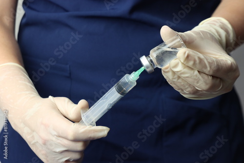 Profissional wearing gloves snorting drug from a vial with a syringe  photo