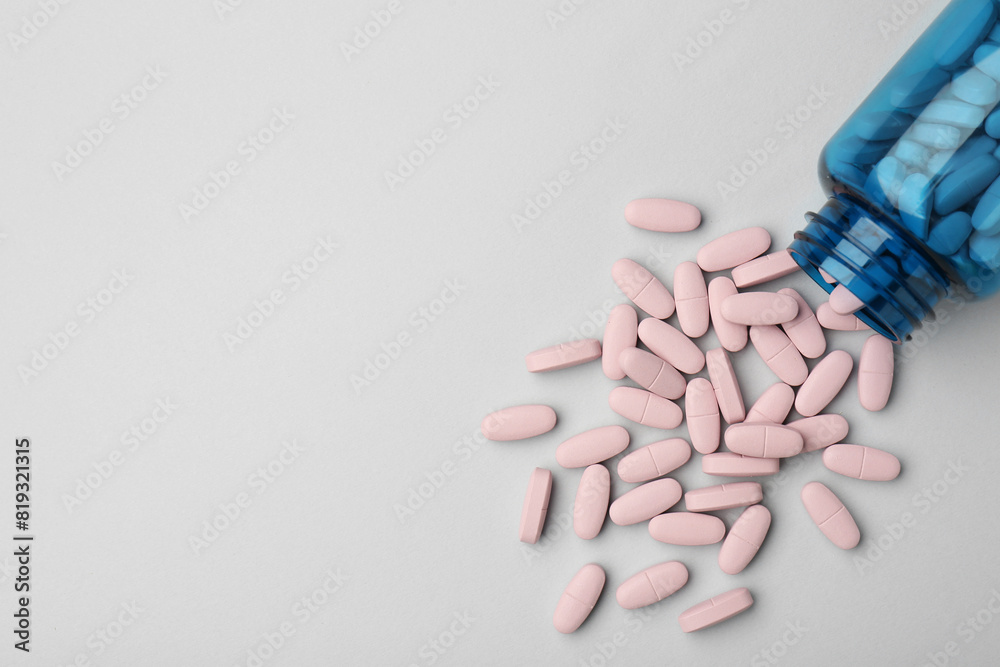 Vitamin pills and bottle on grey background, top view. Space for text