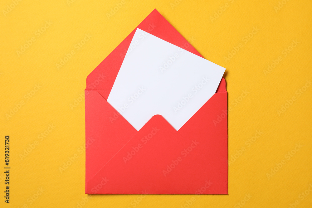 Blank sheet of paper in open letter envelope on orange background, top view Blank sheet of paper in open letter envelope on orange background, top view