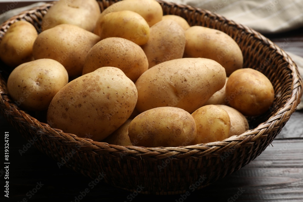 Raw fresh potatoes in wicker basket on wooden table, closeup Raw fresh potatoes in wicker basket on wooden table, closeup