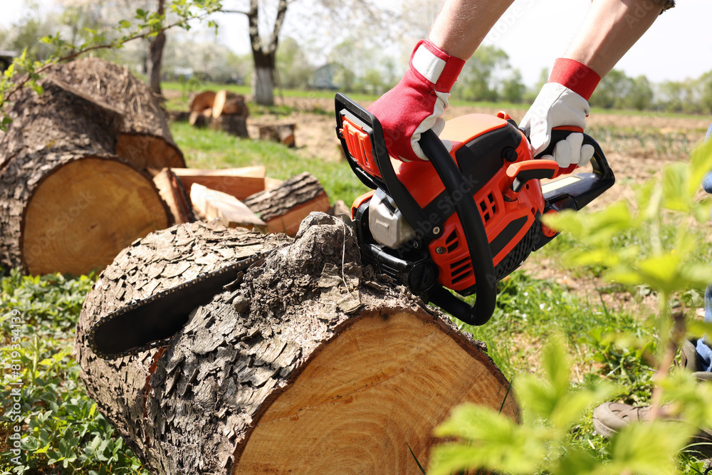 Man sawing wooden log on sunny day, closeup Man sawing wooden log on sunny day, closeup