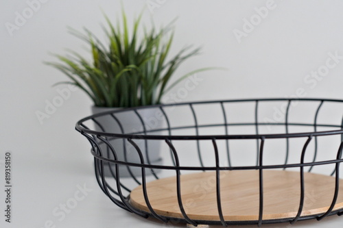 Metal fruit basket with wooden insert with green plant on white background