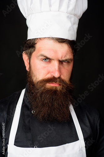 Closeup portrait of serious male chef cook or baker. Professional chef man in cook uniform, hat and apron. Cooking and food preparation. Handsome bearded man in chef uniform. Professional culinary.