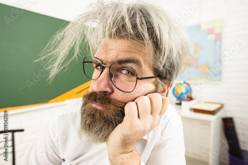 Closeup portrait of serious teacher in glasses at university. Male teacher or professor in school classroom. Learning and education. Handsome bearded teacher in lessons at college. Back to school.
