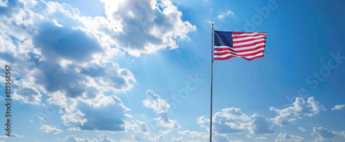 American flag blowing in the wind with a partly cloudy blue sky, USA