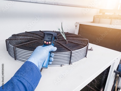 Measuring and checking the temperature of the condenser ventilation using a temperature gun by an engineer photo