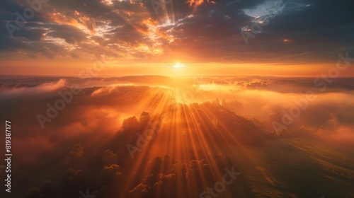 A picturesque sunrise with beams of light piercing through the morning mist and illuminating the sky.