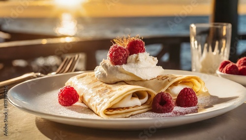 crepes with whipped cream and raspberries on a white plate in a restaurant by the sunset