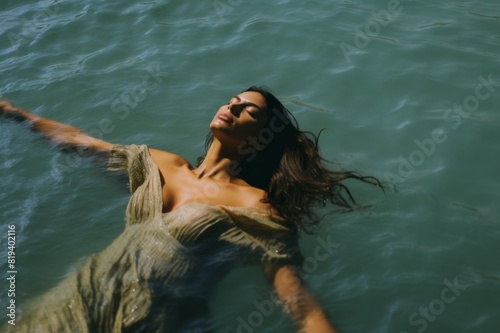 a beautiful indian woman lies back and floats in the ocean © alisaaa