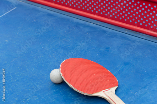 angle view pingpong racket and ball and net on a blue pingpong table at horizontal composition