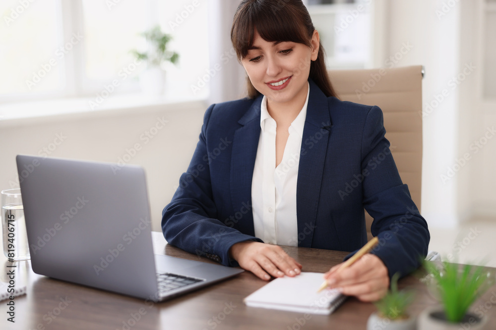 Woman taking notes during webinar at wooden table indoors Woman taking notes during webinar at wooden table indoors