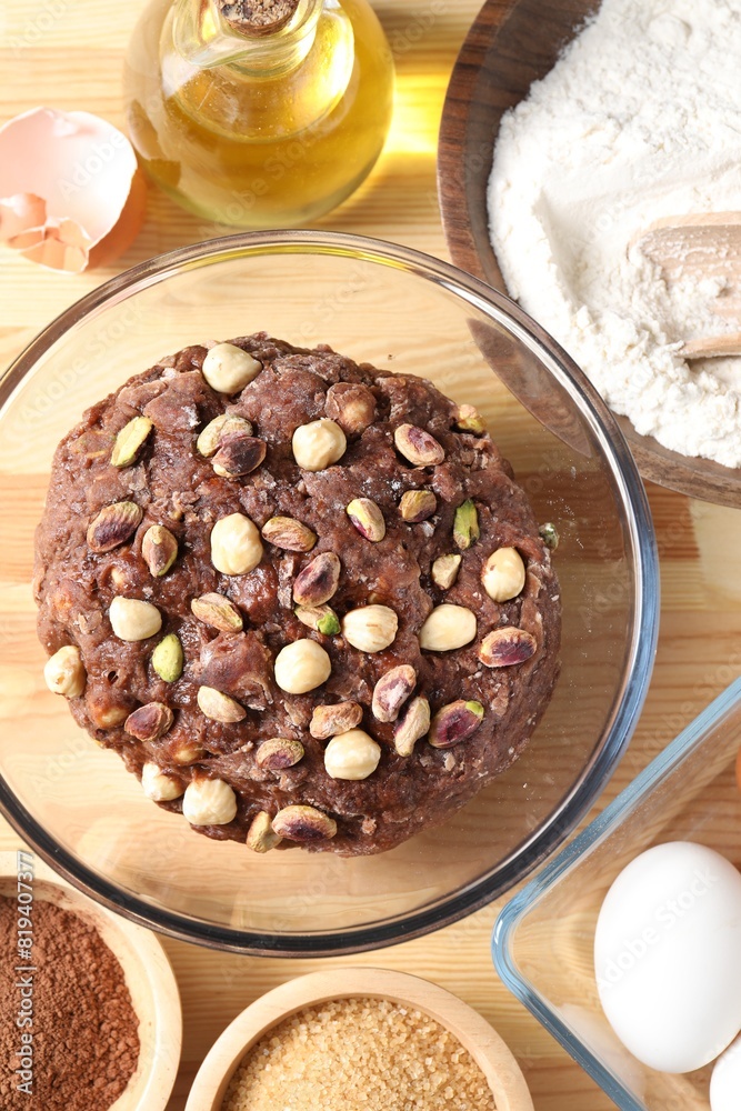 Raw chocolate dough with nuts in bowl and ingredients on wooden table, flat lay Raw chocolate dough with nuts in bowl and ingredients on wooden table, flat lay