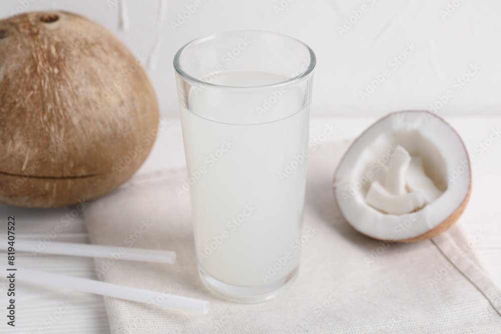 Glass of coconut water and nuts on white table Glass of coconut water and nuts on white table