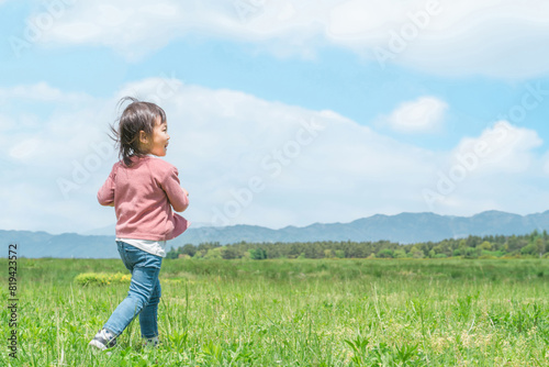 広い公園を走り回る子供（女の子・後ろ姿）
