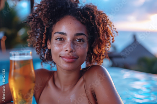 Afro woman having fun in hotel waterpool by relaxing and drinking beer photo