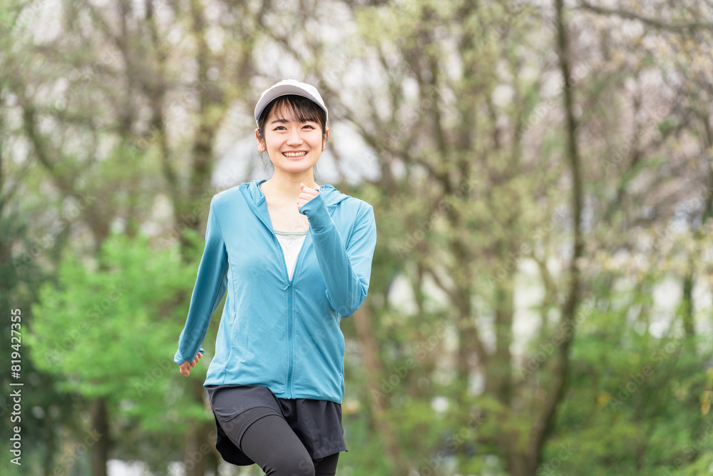 ダイエット・カロリー消費のため公園でウォーキングするスポーツウェアのアジア人女性
