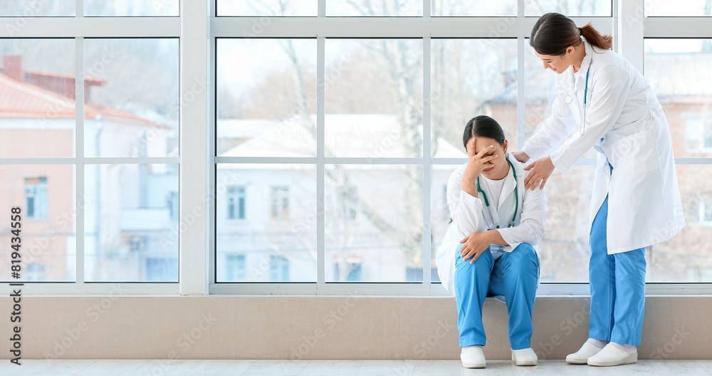 Obraz premium Female Asian doctor calming her colleague in hall of clinic