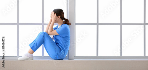 Depressed Asian doctor sitt...