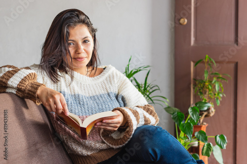 Woman in a coat holding a book looking at the camera