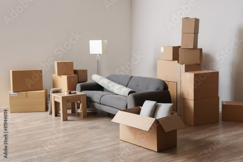 Cardboard boxes with black sofa, rolled carpet and table in living room on moving day © Pixel-Shot