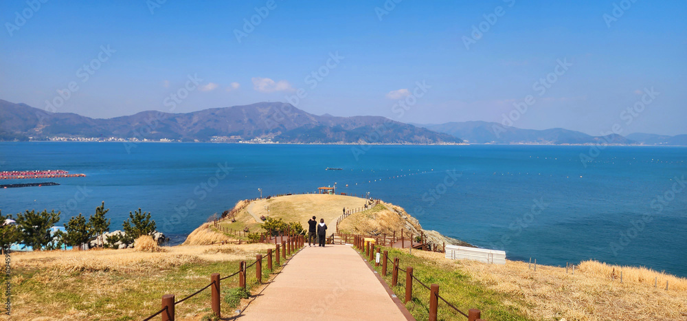 Naklejka premium Calm waves, blue sky, island on the sea, hill road, lover, monitor background image, clean nature, unpolluted environment