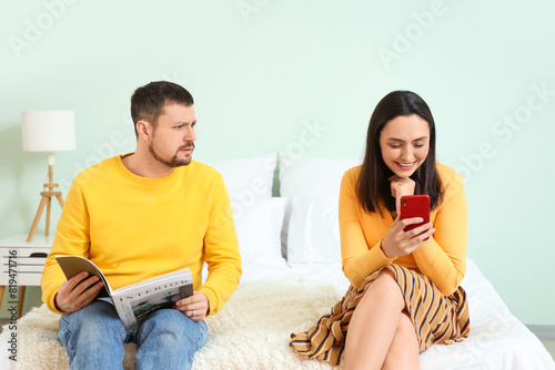 Young woman texting lover and her husband in bedroom. Cheating concept