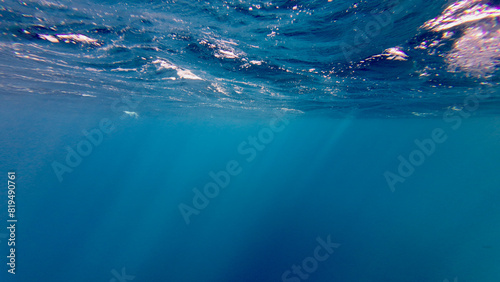 Sectional view of the ocean. Water texture. Rays of the sun against the background of the sea. The sun's rays pass through the water at the surface of the sea. photo