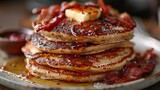 A stack of buttermilk pancakes with butter and a side of crispy bacon..stock photo