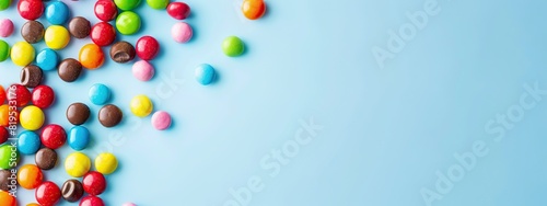 Colorful round candies scattered on a light blue background. Sweet food concept creates a lively and enjoyable atmosphere