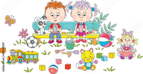 Funny little girl and boy with a puppy sitting on a bench in a summer park and playing their smartphones among toys scattered around, vector cartoon illustration on a white background