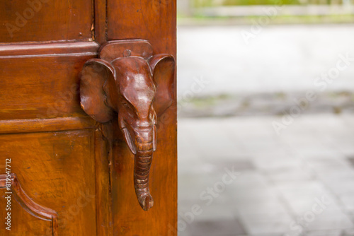 The door of the house made of wood with an elephant shaped handle was open