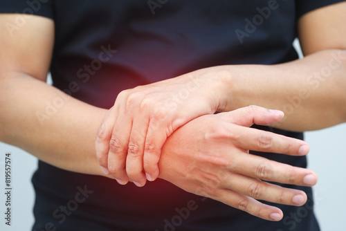 Closeup of male arms holding his painful wrist caused by prolonged work office syndrome. rheumatoid arthritis  gout or sprain weakness and tingling. Health care concept.