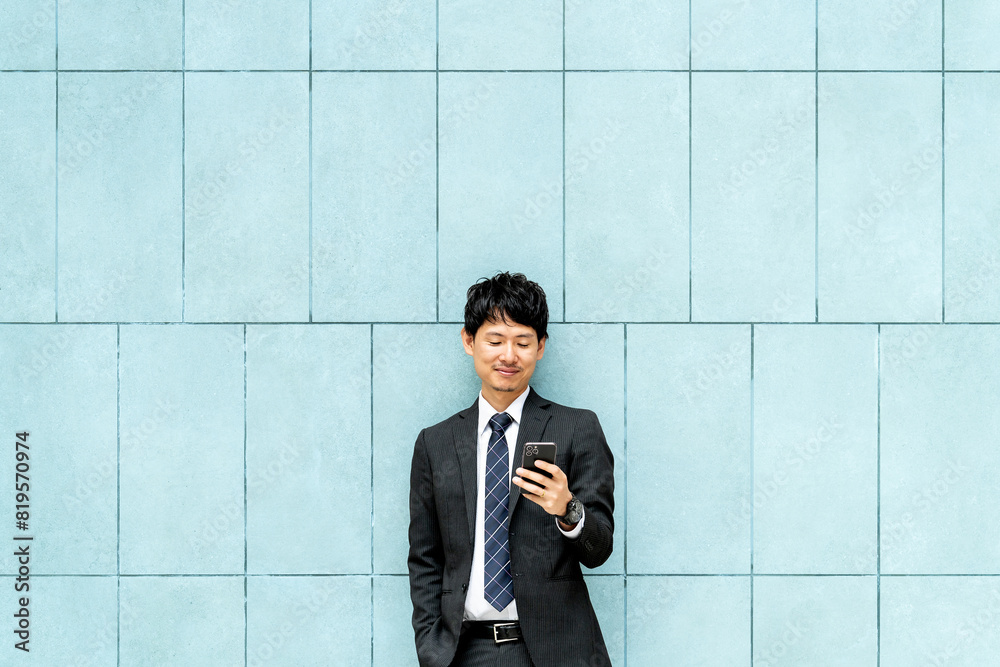 スマホの画面を見る笑顔の男性ビジネスマン スマホの画面を見る笑顔の男性ビジネスマン