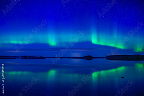 Northern lights dancing over calm lake in Farnebofjarden park in north of Sweden. photo