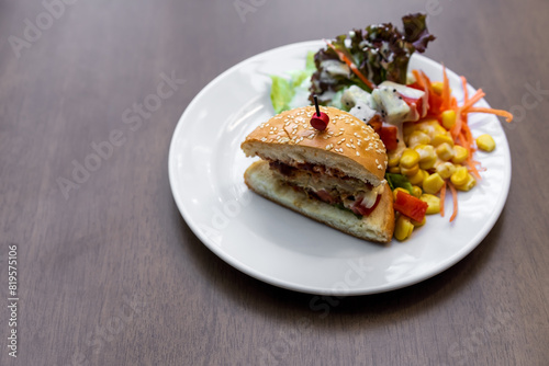 hamburger white sesame or chicken burger cut in half with vegetable and fruits salad by ripe papaya sweetcorn watermelon lettuce and dragon fruit for diet food in plate on wooden table with copy space
