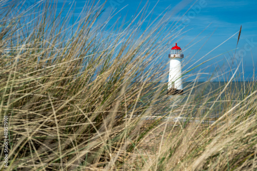 The sand dunes  and the grade II listed building Point of Ayr Lighthouse at Talacre beach in Wales on a sunny summer day.