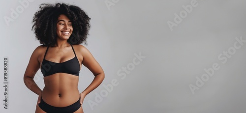 Happy young afro-american woman feeling positive in her natural body. Young adult black girl smiling cheerfully while standing in underwear on a plain background. accepting natural shapes and curves