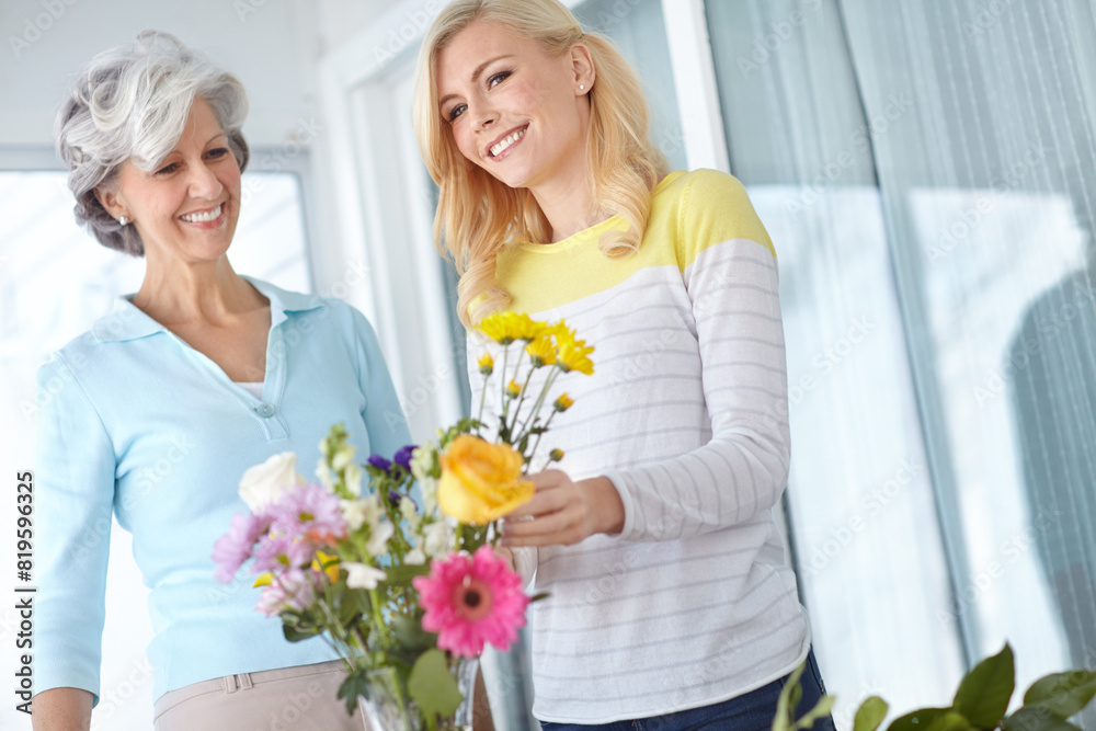 Smile, mom and happy woman with flowers in home together with joy, love and wellness for affection. Mothers day, senior and daughter bonding in lounge with family, parent and gift present in Germany Smile, mom and happy woman with flowers in home together with joy, love and wellness for affection. Mothers day, senior and daughter bonding in lounge with family, parent and gift present in Germany