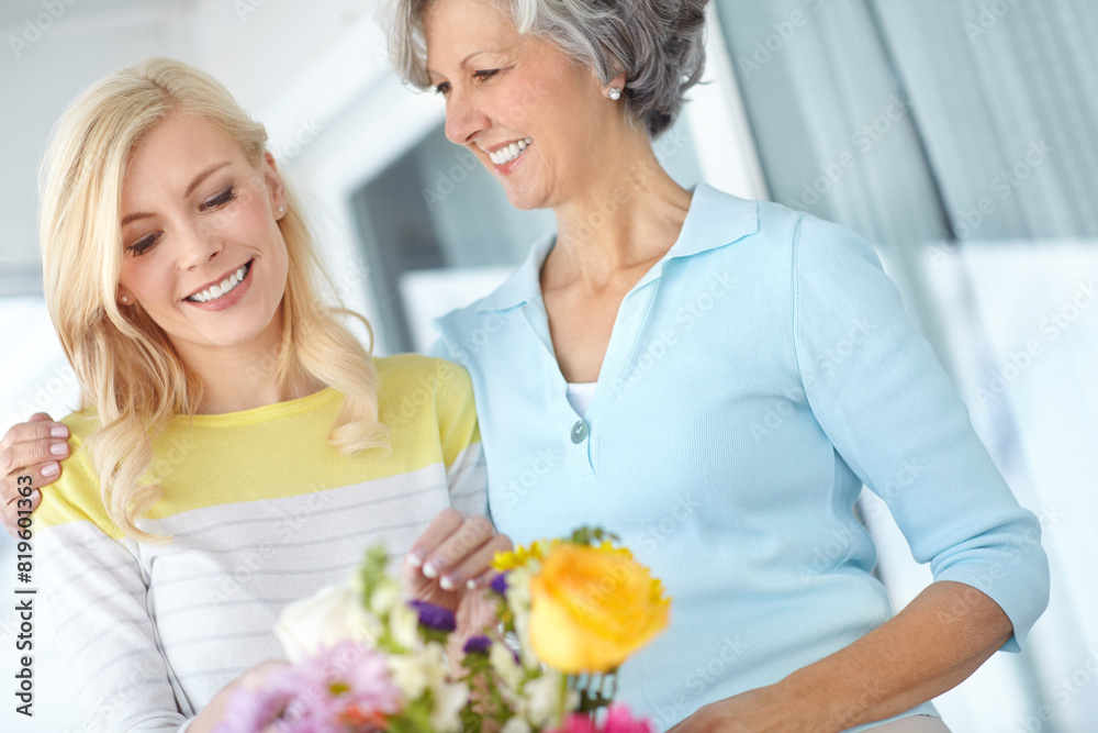 Hug, parent or happy woman with flowers in house together with love, pride and wellness for gardening. Mothers day, mature and daughter bonding in home with family, mom or gift present in Germany Hug, parent or happy woman with flowers in house together with love, pride and wellness for gardening. Mothers day, mature and daughter bonding in home with family, mom or gift present in Germany