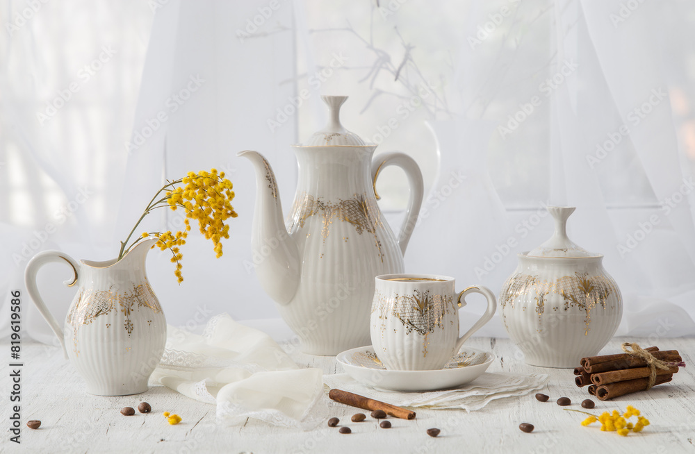 Modern still life with a coffee set and a spring mimosa branch on a light windowsill Modern still life with a coffee set and a spring mimosa branch on a light windowsill
