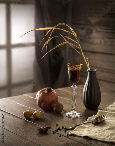 Still life with pomegranate and liqueur in a glass on a wooden table