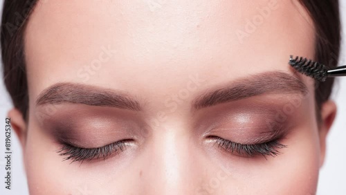 Makeup artist combs eyebrows before coloring in a beauty salon. Professional make-up and cosmetic skin care. photo