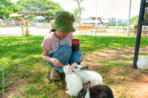 cute little Asian girl feeding a rabbit with Carrot on the farm
