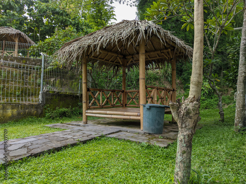 A bamboo hut stands, its roof thatched with lush coconut palm fronds. photo