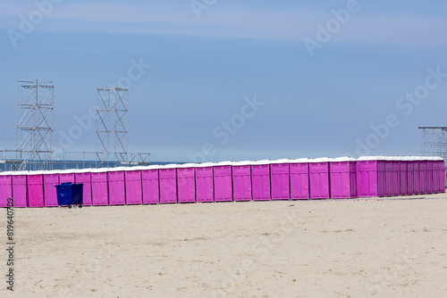 Row of pink portable chemical public toilets on a beach